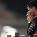 لاندو نوریس با لباس مسابقه نارنجی مک‌لارن در حال شادی پس از کسب قهرمانی.